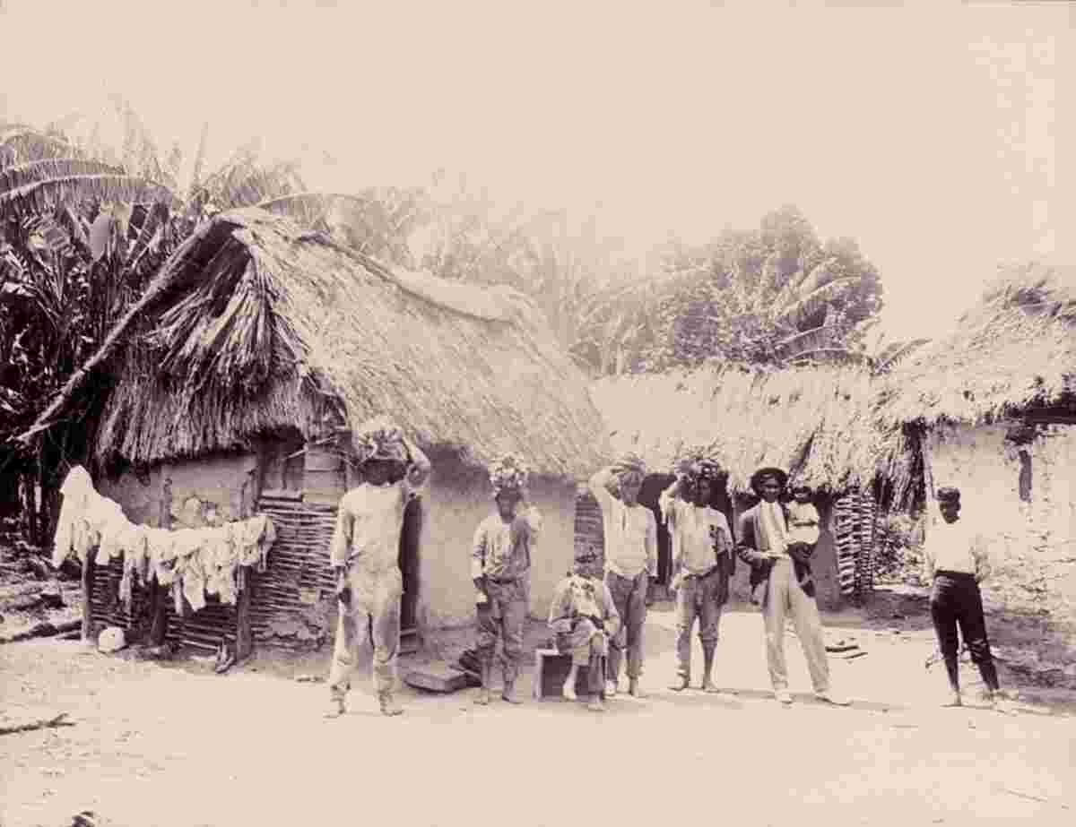 Kingston. Natives in front of thatched-roof houses, circa 1900