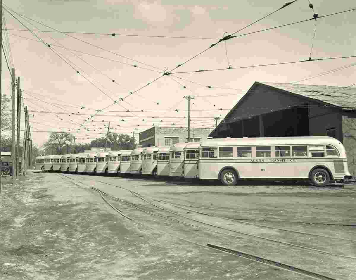 Austin. Line of buses parked outside near tracks, 1940