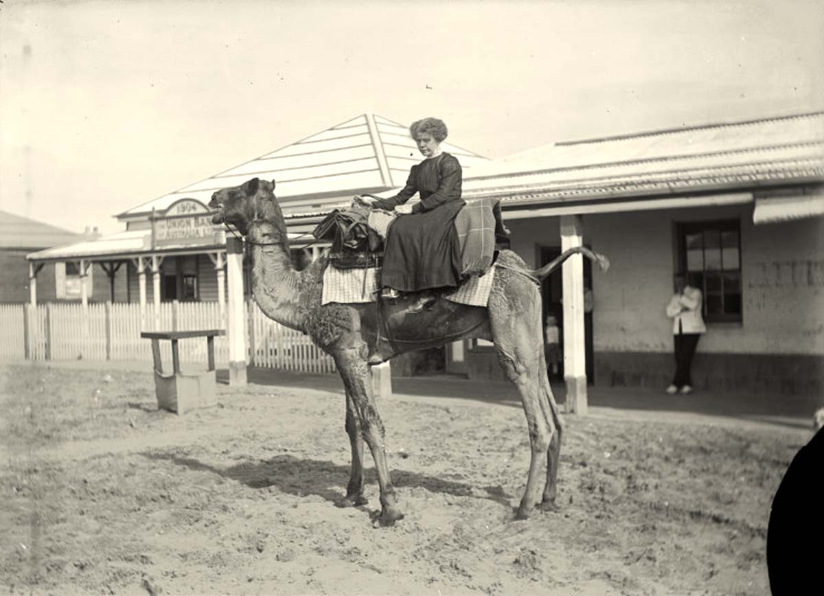 Port Hedland. Riding a camel, in front of the Union Bank, circa 1910