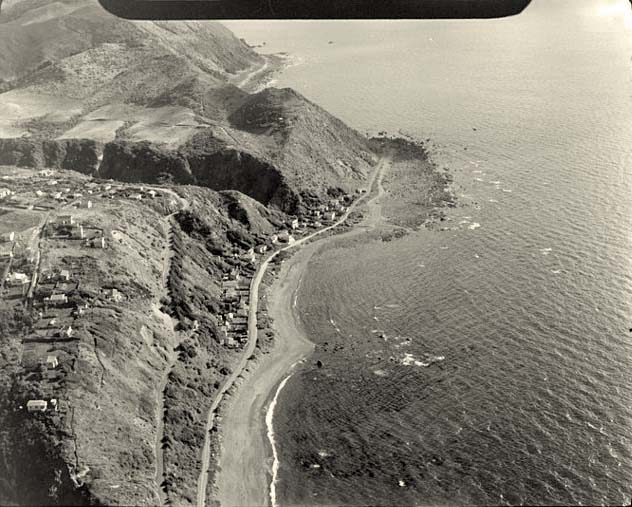 Pukerua Bay. Showing Ocean Parade Road with beach baches, May 1947