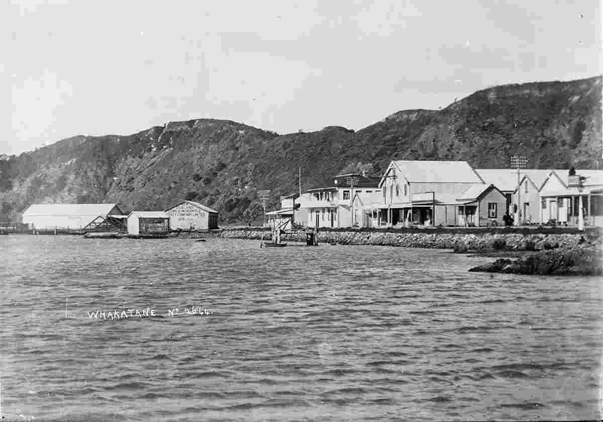 View of Whakatane showing a row of shops and businesses by the Whakatane River, 1900s
