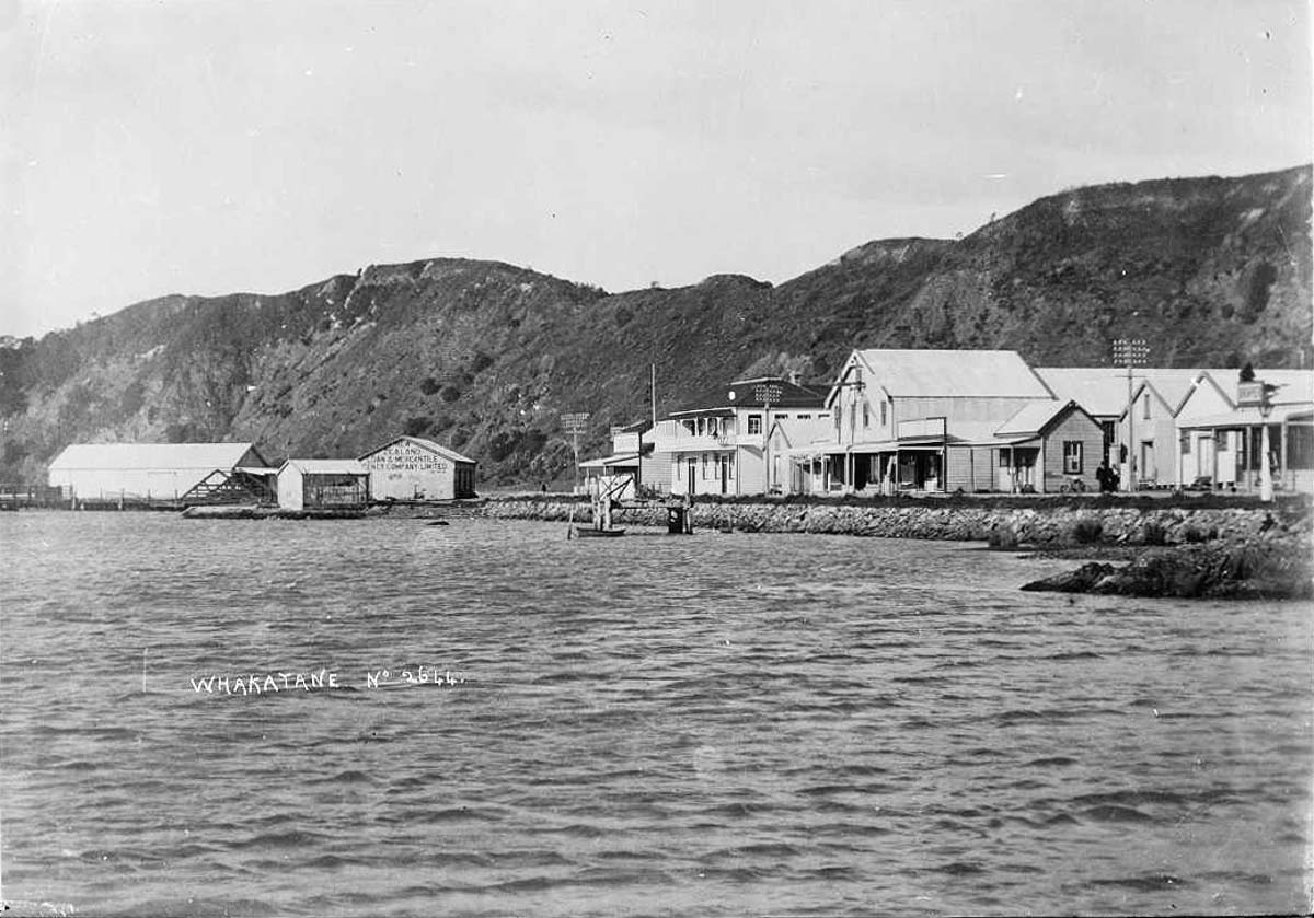 View of Whakatane showing a row of shops and businesses by the Whakatane River, 1900s